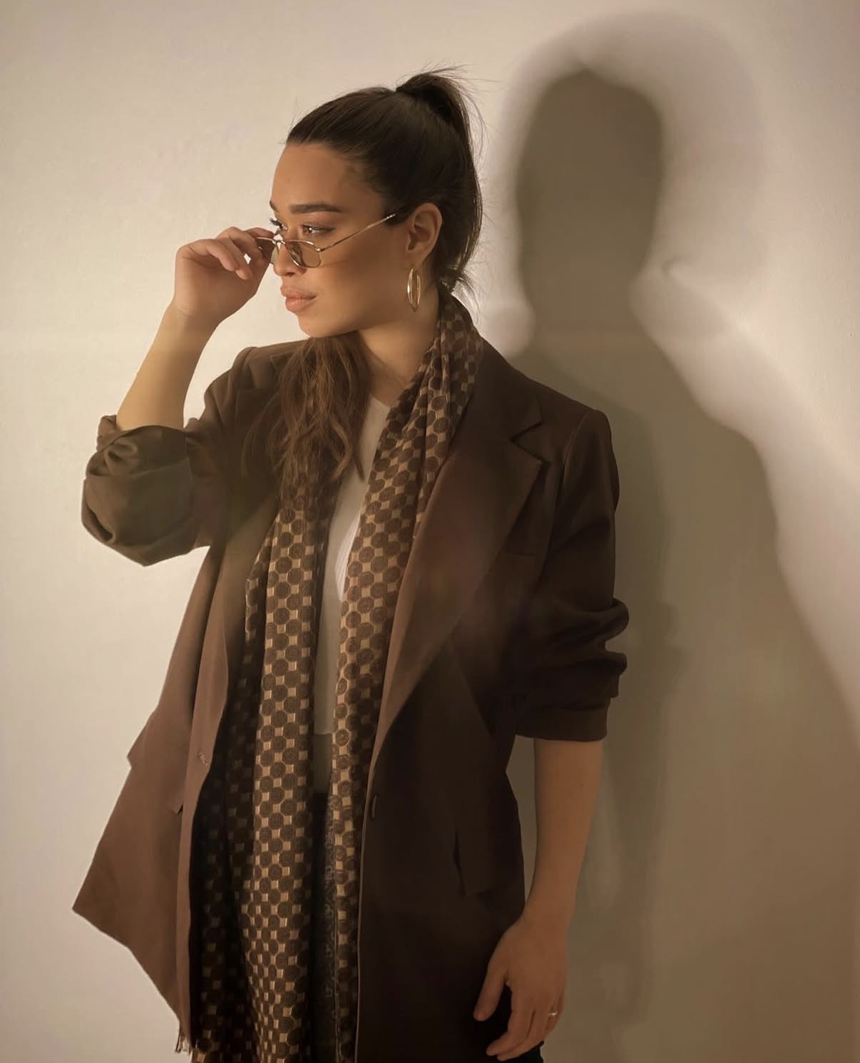 Stylist wearing a tailored brown blazer and printed scarf